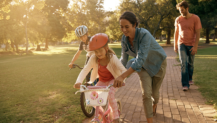 Mother teaching kids to ride bike.